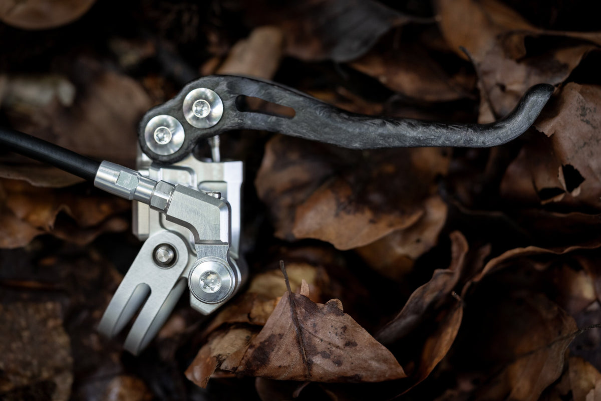 Angled hose fitting on a silver Trickstuff Piccola pump with its carbon lever visible.