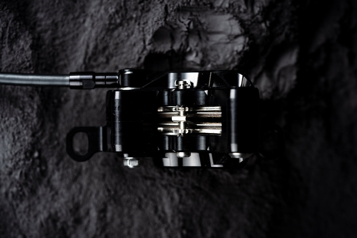 Top view of a black Trickstuff C42 caliper with the pads and retaining bolt visible.