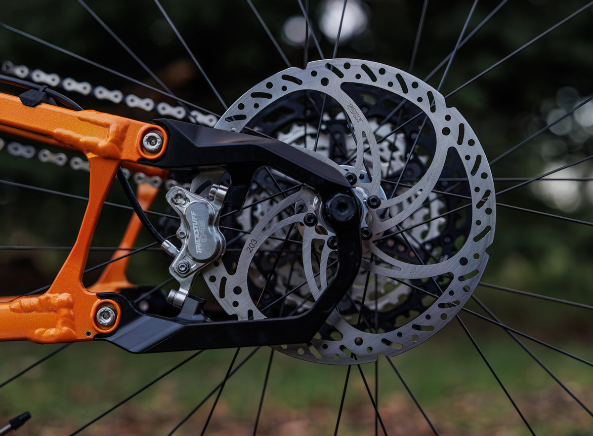 Trickstuff Dächle Heavy Duty rotor marked 203 installed in an orange mountain bike rear wheel.